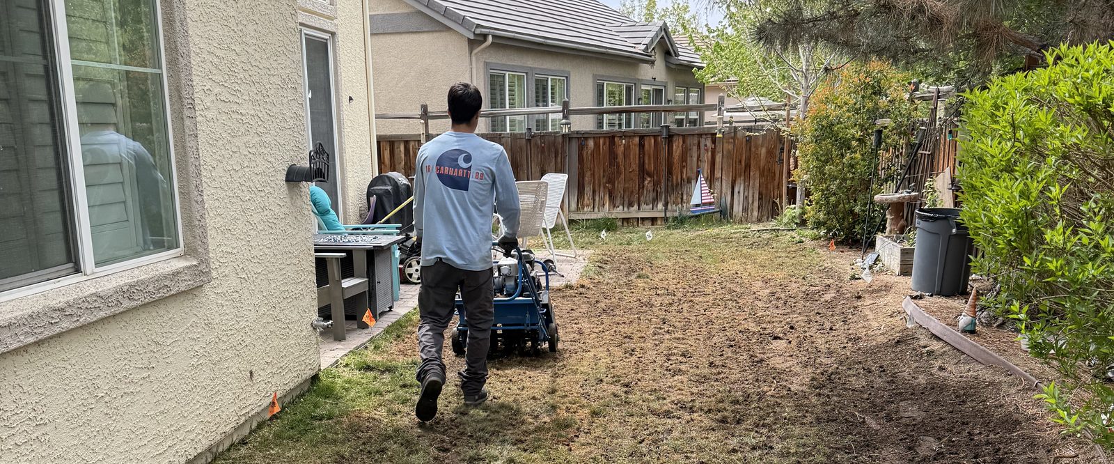 Sierra Lawn Co. crew member pushing a core aerator across a backyard lawn in Sparks, Nevada