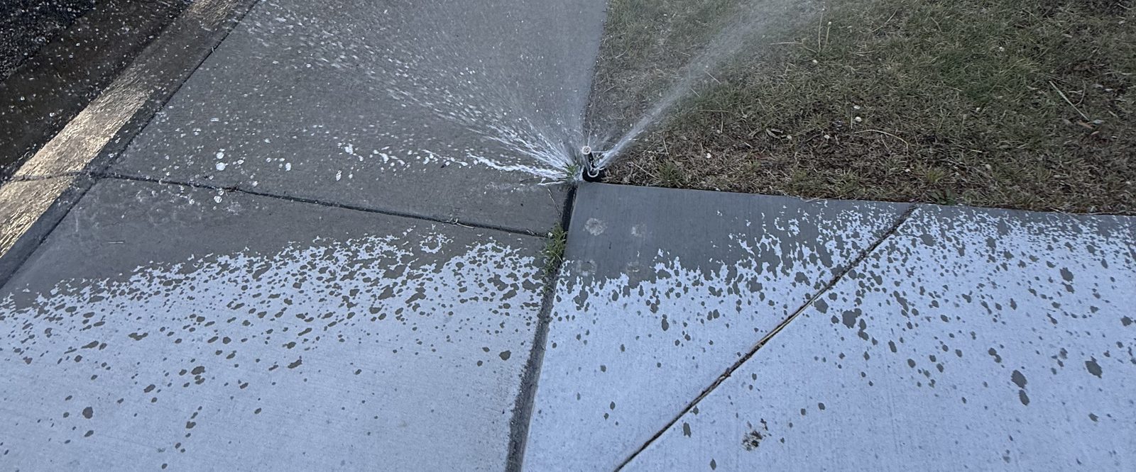 Broken sprinkler head spraying water onto a sidewalk instead of the lawn in Sparks, Nevada